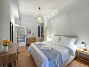 Un dormitorio con una cama blanca grande y una mesa en Acropolis view 4 bedroom flat, en Atenas