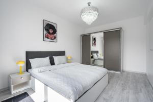 Un dormitorio blanco con una cama grande y un espejo. en Rose Residence 1-1BR Apt-Parking, en Voluntari