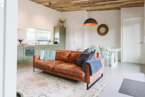 a living room with a brown couch and a kitchen at Vakantiewoning nabij zandstrand Ouddorp VP026 in Ouddorp