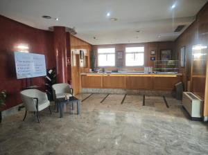 a waiting room with chairs and a table and a counter at Hotel Helmántico in Villares de la Reina