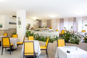a restaurant with white tables and yellow chairs at Hotel Villa Maria in Sirmione