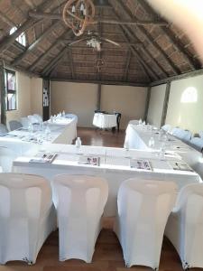 a large room with white tables and white chairs at Dream Catcher Hotel in Gaborone