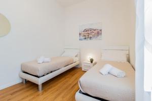 two beds in a room with white walls and wooden floors at Silk & Sunset - City and Lake View with parking in Como