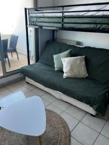 a bedroom with a bunk bed with a couch and a chair at Carnon vue mer, charmant studio plages clim restaurants commerces in Mauguio