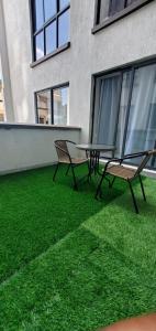 two chairs and a table on a balcony with green grass at Nyayo Haven Suites in Nairobi