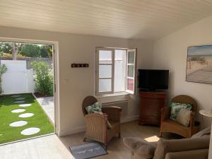 a living room with a couch and chairs and a television at Hotel Les Bois Flottais in Le Bois-Plage-en-Ré