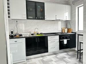 a kitchen with white cabinets and a black dishwasher at Cozy Flat in Praia