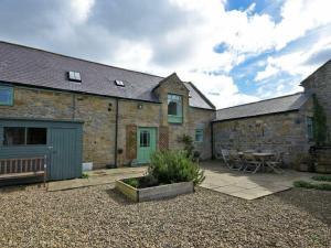 Cette maison en pierre dispose d'une terrasse et d'une table. dans l'établissement Croft Cottage, à Alnwick