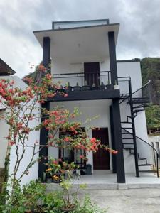 a white building with a staircase and flowers on it at Zico Homestay in Andalas