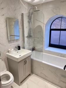 une salle de bain avec un lavabo, des toilettes et une douche dans l'établissement Fletcher - A Converted Church Luxe Apartment, à Gillingham