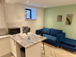 un salon avec un canapé bleu et une cuisine dans l'établissement Fletcher - A Converted Church Luxe Apartment, à Gillingham