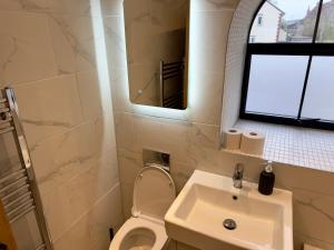 a bathroom with a sink and a toilet and a mirror at Hurley - A Converted Church Luxe Apartment in Gillingham +8 photos