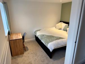 a small bedroom with a bed and a wooden table at Hurley - A Converted Church Luxe Apartment in Gillingham
