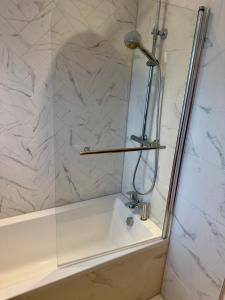 a shower with a glass door and a bath tub at Hurley - A Converted Church Luxe Apartment in Gillingham