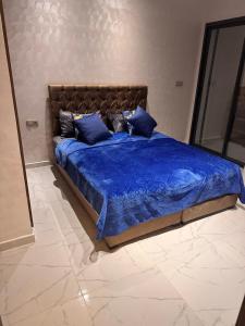 a bedroom with a bed with blue sheets and pillows at Taghrid 3 in Kenitra