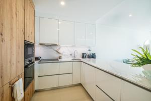 a white kitchen with white cabinets and a sink at Sob O Mar III in Armação de Pêra