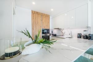 a white kitchen with a vase on a counter at Sob O Mar III in Armação de Pêra