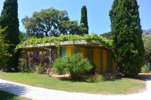 a building covered in plants and flowers in a yard at Agréable villa fleurie sur l'ile de Porquerolles in Porquerolles