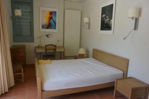 a bedroom with a bed and a table and a desk at Agréable villa fleurie sur l'ile de Porquerolles in Porquerolles