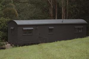 a small shed with a tin roof on a hill at Train Carriage Tiny Home in the Byron Hinterland in Alstonvale
