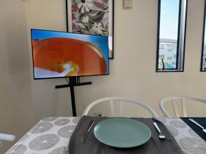 une salle à manger avec une table et une télévision au mur dans l'établissement Mark的足立江北站民宿, à Tokyo
