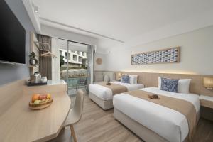 a hotel room with two beds and a table with a bowl of fruit at Andaman Beach Hotel Phuket - Handwritten Collection in Patong Beach +38 photos