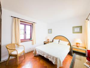 een slaapkamer met een bed, een stoel en een raam bij Villa Dunn Mar V3 by YHA in Cabanas de Tavira