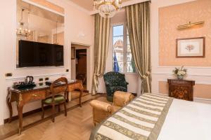 a bedroom with a bed and a desk and a television at Hotel Bernini Palace in Florence
