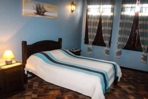 a bedroom with a bed with blue walls and windows at OYO Hotel La Dolce Vita, Rio das Ostras in Rio das Ostras