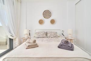 Un dormitorio blanco con una cama con toallas. en Icon Marina D, en La Herradura 25 fotos más