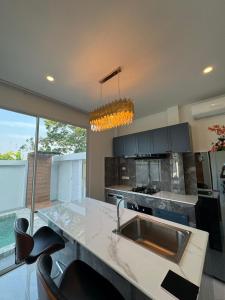 Una cocina con fregadero y una encimera con sillas. en Nacha Villa, en Rawai Beach