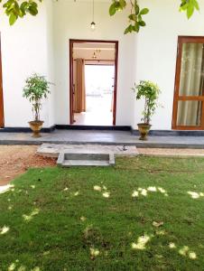 une porte ouverte vers un bâtiment avec deux plantes en pot dans l'établissement Crush River Villa Hikkaduwa, à Hikkaduwa