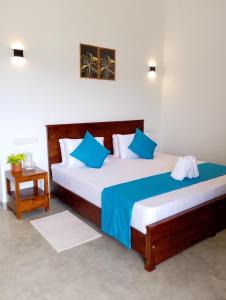 een slaapkamer met twee bedden met blauwe en witte kussens bij Crush River Villa Hikkaduwa in Hikkaduwa