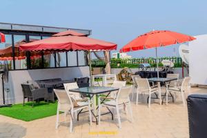 a patio with tables and chairs and red umbrellas at BEST HOTEL Aero-Batignoll in Brazzaville
