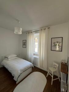 Un dormitorio con una cama y una silla y una ventana. en Appartement de la Diane, en Villers-Cotterêts