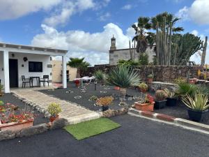 un giardino con piante in vaso e un muro di pietra di Mardelava a Tinajo