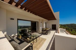 a patio with a table and chairs on a balcony at Modern penthouse with two terraces, jacuzzi and sea, lake and mountain views, in Almazara Hills in Istán