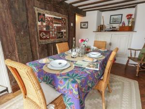 ein Esszimmer mit einem Tisch und einem lila Tischtuch in der Unterkunft Cobblers Cottage in Weymouth