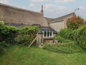 ein altes Haus mit Strohdach und einem Garten in der Unterkunft Cobblers Cottage in Weymouth