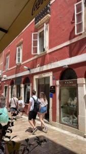 a group of people walking in front of a red building at Canta Amore Suites in Zadar