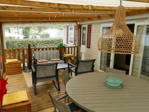 a patio with a table and chairs and a chandelier at Jolie mobilhome 331 in Gastes
