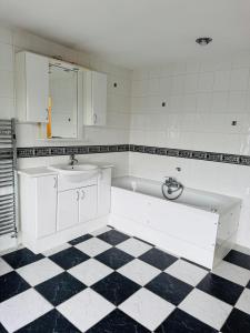 a white bathroom with a sink and a tub at Gordon Avenue Guest House HA7 London in Busheyheath