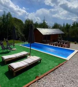 a swimming pool with chaise lounges and a house at Hellena in Sarajevo