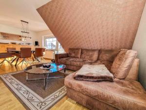 a living room with a brown couch and a table at Strandmuschel in Greetsiel