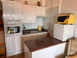 una pequeña cocina con armarios blancos y microondas en Vista Mar y piscina climatizada, en Arona