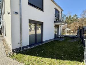 a white house with glass doors and a yard at MontiRooms- Apartment nahe Berlin & Natur in Woltersdorf