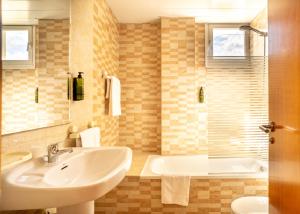 a bathroom with a sink and a tub at Aparthotel Ona Palamós in Palamós