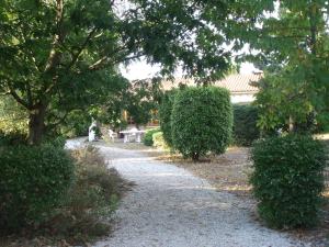 un chemin dans un jardin avec des buissons et des arbres dans l'établissement Capriga, à Arès
