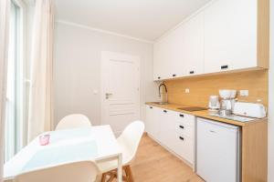 a kitchen with white cabinets and a table and chairs at Comfortable 3city Studios in Sopot by Noclegi Renters in Sopot +8 photos