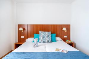 a white teddy bear sitting on top of a bed at Aparthotel Ona Palamós in Palamós